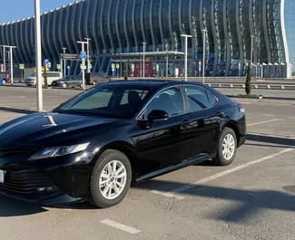 Vooraanzicht van een huurauto Toyota Camry op de luchthaven van Simferopol, Krim ✓ Auto #1825. ✓ Transmissie Automatisch TM ✓ 0 beoordelingen.