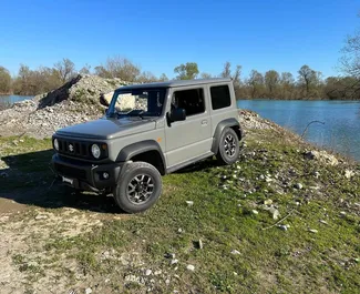 Vooraanzicht van een huurauto Suzuki Jimny op Podgorica Luchthaven, Montenegro ✓ Auto #15693. ✓ Transmissie Automatisch TM ✓ 0 beoordelingen.