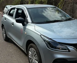 Vooraanzicht van een huurauto Suzuki Baleno op de luchthaven van Goa, Goa ✓ Auto #16196. ✓ Transmissie Handmatig TM ✓ 0 beoordelingen.